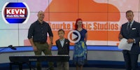 a group of people standing next to a piano in front of a tv