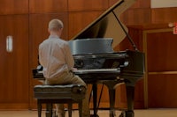 a young man playing a piano in a large room