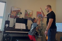 a man and a boy standing in front of a piano